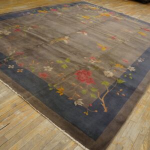 Gray rug featuring a colorful floral and bird pattern with a dark blue border on worn wood flooring.
