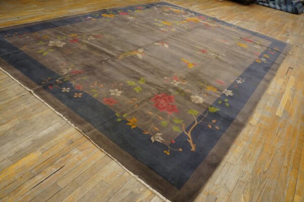 Gray rug featuring a colorful floral and bird pattern with a dark blue border on worn wood flooring.