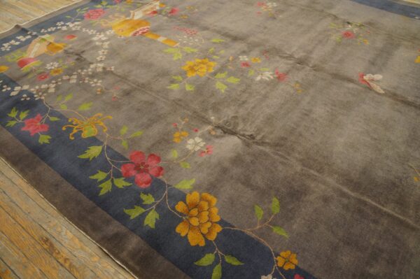 Grey field rug with scattered yellow, red, and pink floral patterns and a wide blue border on wood flooring.