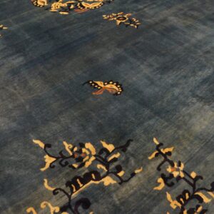 A deep blue rug with striations, detailed with stylized butterflies and flowering branches in gold and black.