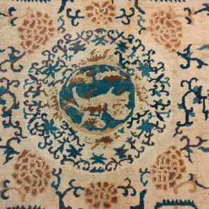 Ornate rug detail featuring a teal and brown circular motif surrounded by floral designs on a beige pile.