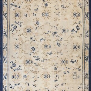 Rectangular rug with a cream field, scattered blue and tan floral medallions, and a wide indigo border.