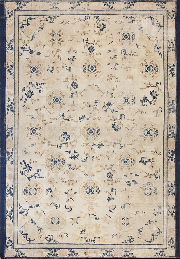 Rectangular rug with a cream field, scattered blue and tan floral medallions, and a wide indigo border.