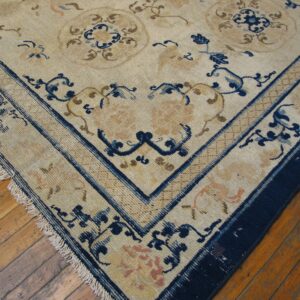 Low-pile rug with a beige ground, detailed blue and tan floral motifs, resting on hardwood floors.