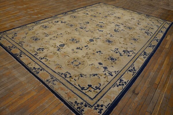 Large tan rug with blue floral and medallion patterns on rustic wood flooring.