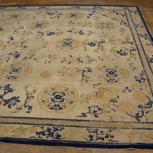 Large cream rug with intricate blue, gold, and peach floral patterns on a wooden plank floor.