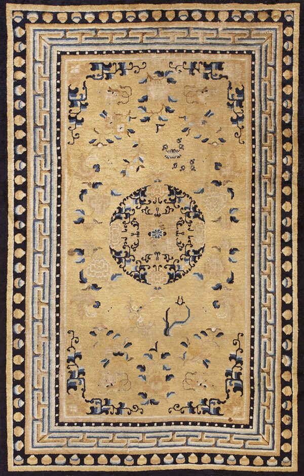 Rectangular golden beige rug with dark blue stylized floral patterns and a wide geometric border.