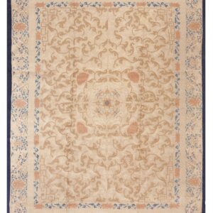 Beige rug featuring ornate camel, coral, and blue scrolling floral patterns and a dark navy edge.