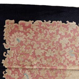 Scalloped floral and scrollwork design in rose and beige set against a contrasting black rug border.