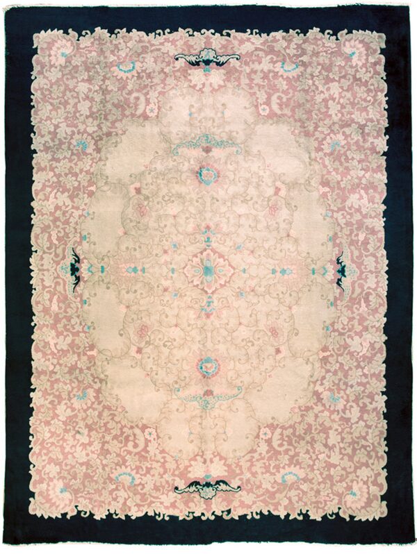 Ornamental rug featuring a pale pink and beige field with a centralized pattern and wide dark outer border.