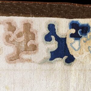 A cream rug border features thick pile and stylized shapes in navy blue, light blue, and dusty tan.