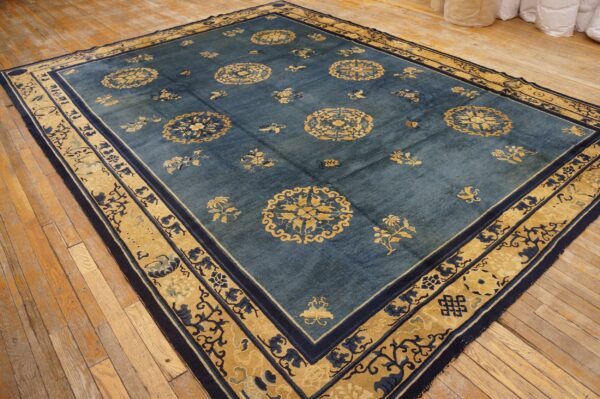 Dark blue rug with contrasting yellow-gold medallions and ornate borders sits on rustic wood plank flooring.