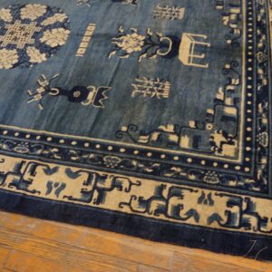 A traditional indigo and tan rug featuring ornate motif borders rests on hardwood planks.