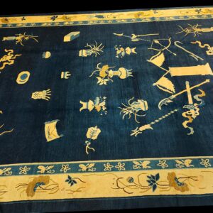 Low pile navy blue rug with gold and teal borders framing scattered symbolic object motifs.
