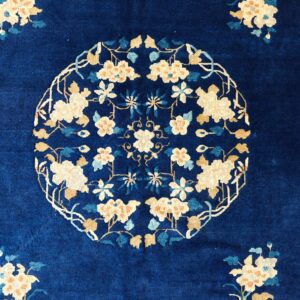 High-pile rug featuring a dense indigo field with an intricate central medallion of cream and tan flowers.