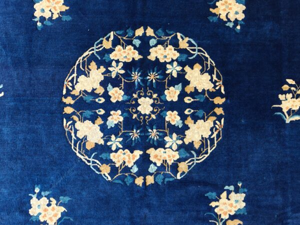 High-pile rug featuring a dense indigo field with an intricate central medallion of cream and tan flowers.