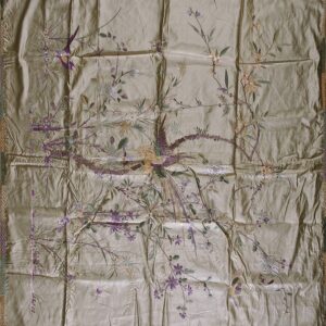 Square, wrinkled taupe textile with intricate purple, tan, and green embroidery of birds and flowers.