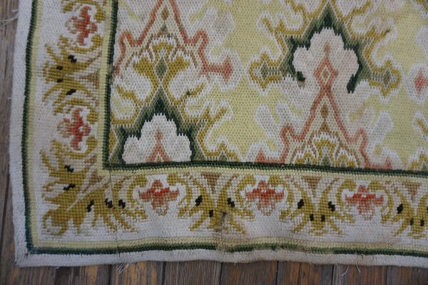 Low-pile rug detail showing yellow, white, green, and orange stylized floral patterns on a wood floor.