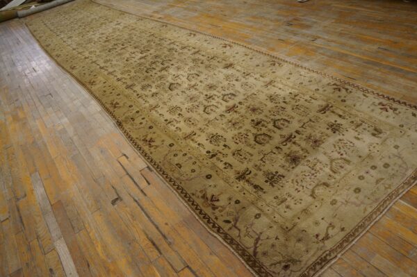 Long beige gallery rug featuring a muted all-over floral pattern lies on distressed plank hardwood flooring.