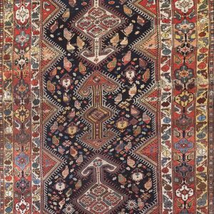 A detailed tribal rug with a navy blue field and complex stylized patterns, framed by thick red and gold borders.