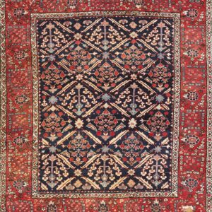 Traditional navy and red rug features a detailed lattice pattern with floral motifs, showing visible wear and damage on the border.