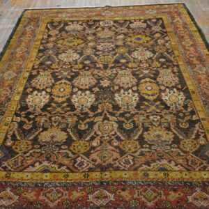 Low-pile rug with a dark field and colorful medallions sits on a worn, light-toned wood plank floor.