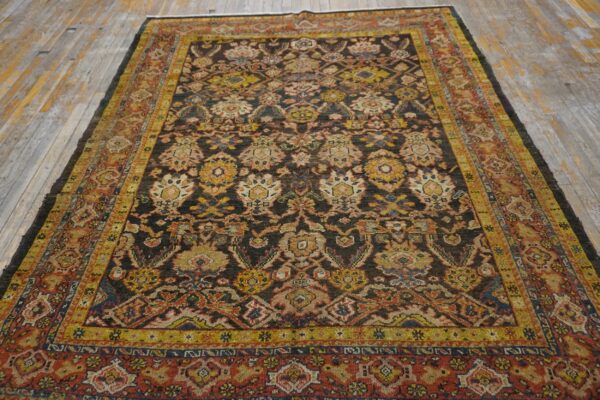 Low-pile rug with a dark field and colorful medallions sits on a worn, light-toned wood plank floor.