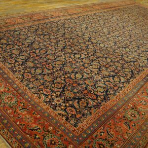 Traditional low-pile rug featuring a navy blue field with intricate floral patterns and a wide burnt red border.