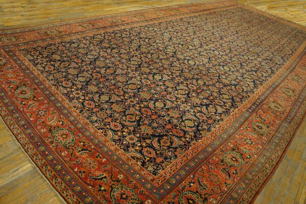Traditional low-pile rug featuring a navy blue field with intricate floral patterns and a wide burnt red border.
