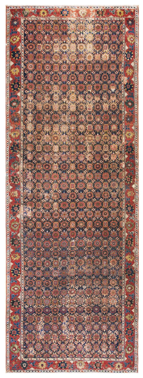 Distressed low-pile rug featuring a dense repeating geometric pattern on a navy field with thick red borders.