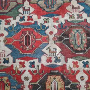 Detailed view of a vibrant traditional rug pattern with stylized animal figures, red, blue, and gray colors.