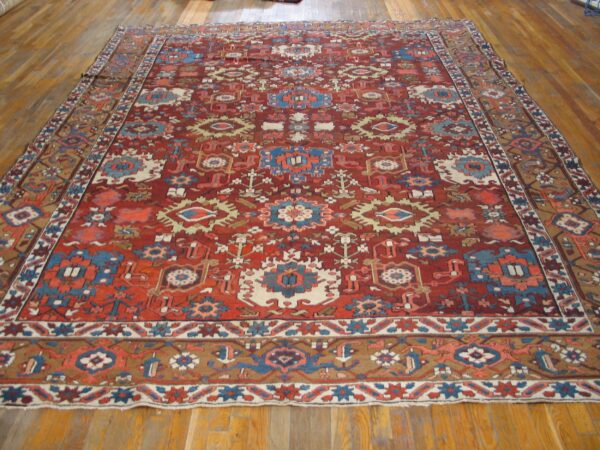 Traditional deep red rug with blue, cream, and tan tribal geometric motifs lying on wood floors.