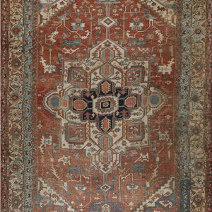 Rust red rug with a prominent navy, blue, and cream geometric central medallion and layered borders.