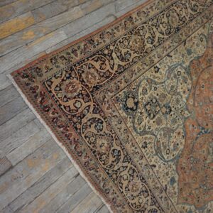 Ornate floral rug in rust, navy, and beige lies on distressed gray wood plank flooring.