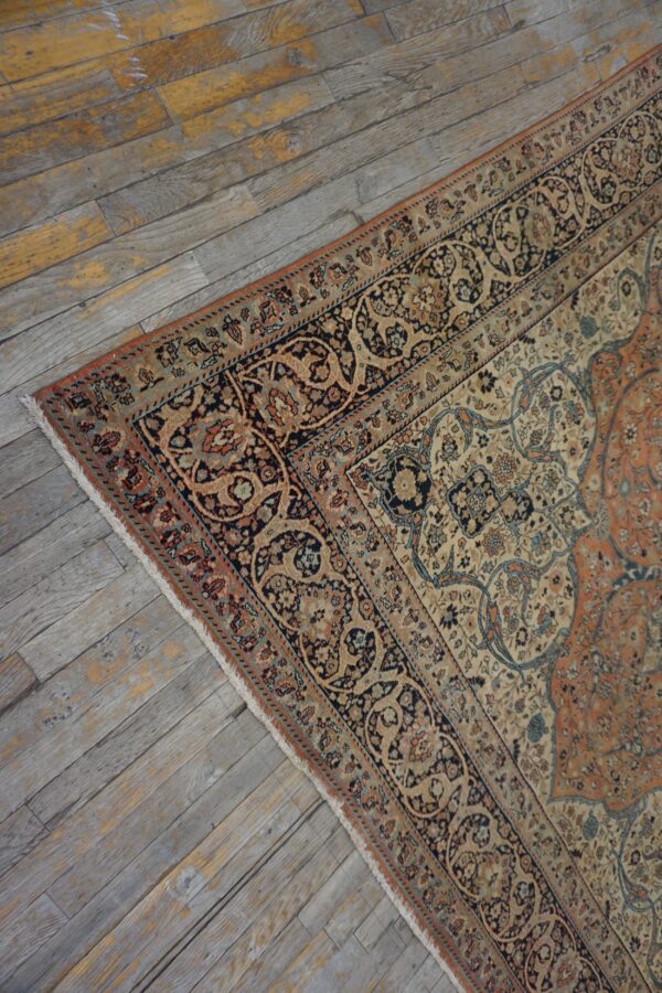 Ornate floral rug in rust, navy, and beige lies on distressed gray wood plank flooring.