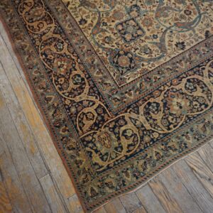Ornate cream rug featuring navy, teal, and rust floral patterns rests on worn wood planks.