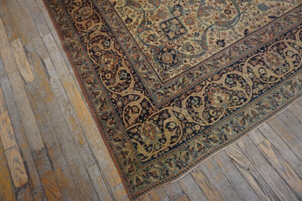 Ornate cream rug featuring navy, teal, and rust floral patterns rests on worn wood planks.