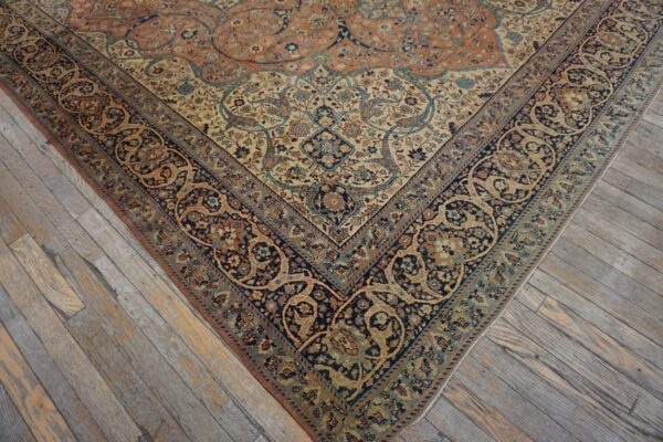 Ornate navy, cream, and rust traditional rug rests on distressed gray hardwood flooring.