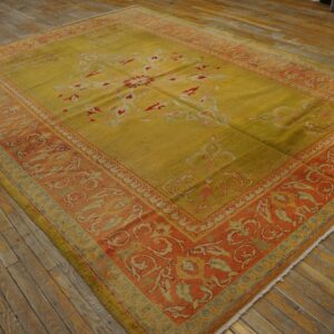 Low-pile rug in golden chartreuse and terracotta tones with scrolling floral motifs on distressed wood.