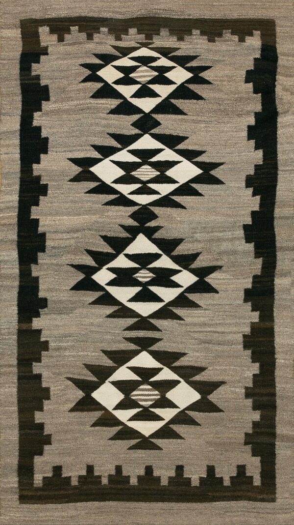Gray flatweave rug with stacked black and white serrated diamond medallions and a dark stepped border.