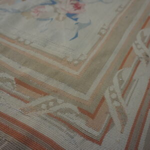 Large cream rug featuring pale blue trellis, floral sprays, and a round central medallion on wood floors.