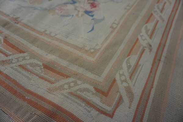 Large cream rug featuring pale blue trellis, floral sprays, and a round central medallion on wood floors.