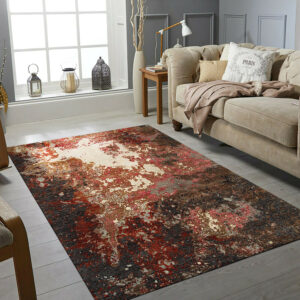 Abstract high-low pile rug in steel gray, dark brown, and rust sits on a pale wood floor.