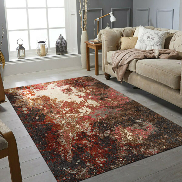 Abstract high-low pile rug in steel gray, dark brown, and rust sits on a pale wood floor.