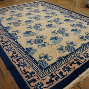 Cream rug featuring repeating blue cloud and round symbols, surrounded by a complex pink and navy border.
