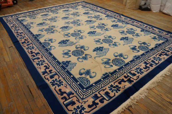 Cream rug featuring repeating blue cloud and round symbols, surrounded by a complex pink and navy border.