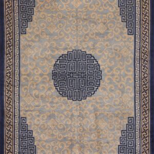 Navy blue bordered rug with a gray field, gold scrolling patterns, and a central fretwork medallion.