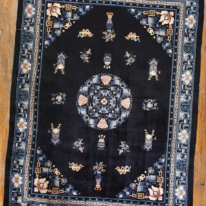 Navy rug with intricate blue, pink, and tan floral borders and a central medallion on hardwood flooring.