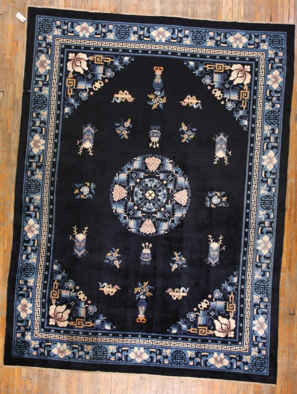 Navy rug with intricate blue, pink, and tan floral borders and a central medallion on hardwood flooring.