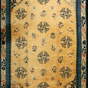 Golden yellow rug with scattered blue florals, flanked by complex blue and tan decorative borders.